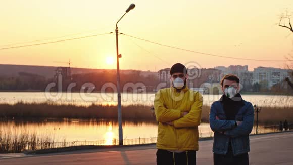 新的Covid19概念两个朋友带着防护面罩站在公园中央的摄像头前视频的预览图