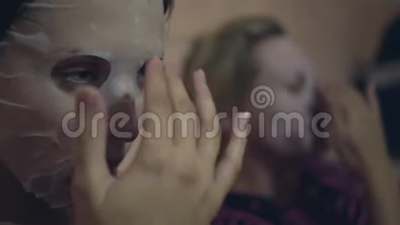 两个女人在脸上涂了一个日本化妆组织面具抚平了脸上的面具视频的预览图