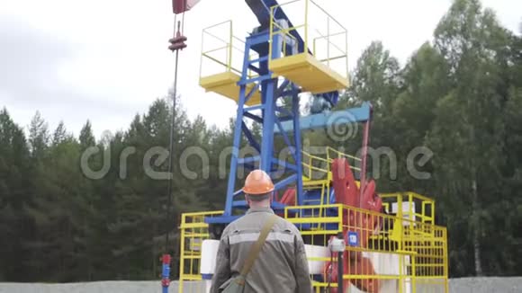 油田技术工人站在原油泵机组前工程师监督工业油泵千斤顶石油视频的预览图