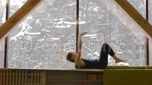 一个年轻英俊的白人男子正在一扇大窗户前做瑜伽它进行各种练习以加强和视频的预览图