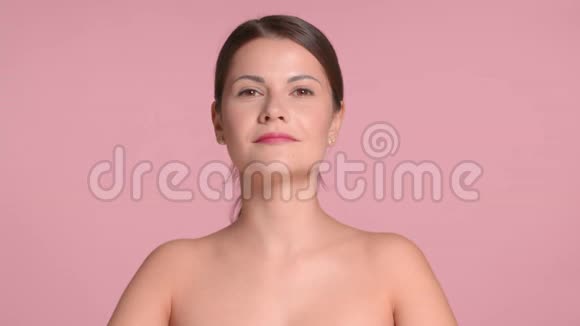 30岁的黑发女人穿着精致的上衣在粉色背景的工作室里搭配着理想的皮肤视频的预览图