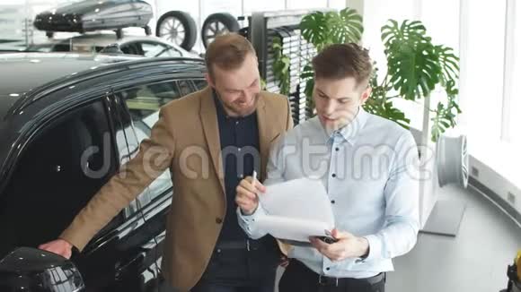 英俊的年轻汽车销售员帮助客户选择视频的预览图