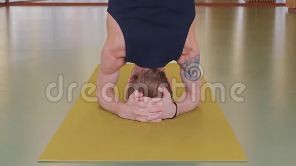 一个年轻英俊的高加索男人正在做瑜伽在黄色的工作室里做伸展和柔韧性练习吗视频的预览图