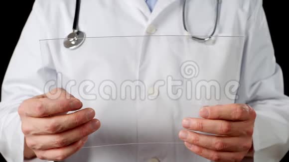 医务人员手拿透明平板电脑在白色外套背景男性医生的手使用未来视频的预览图