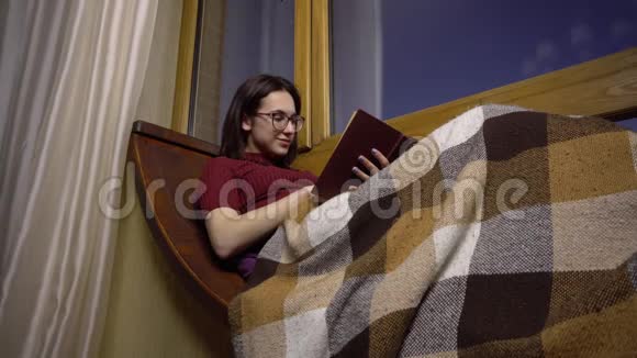 一个年轻的女人正在看书一个女孩躺在窗边的窗台上手里拿着一本书晚上出去视频的预览图