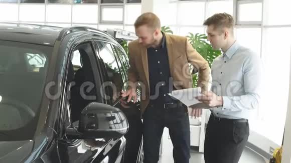 英俊的年轻汽车销售员帮助客户选择视频的预览图