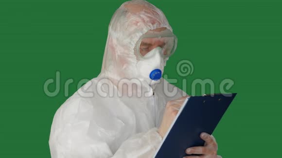 穿着防护服装的医务人员和在剪贴板上写面具生物工程师安全套装在夹板上书写视频的预览图
