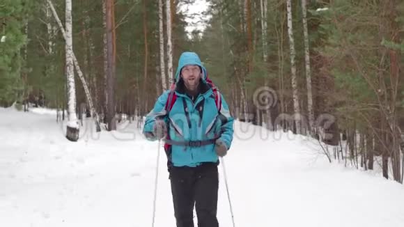 背着背包散步的人在冬天的森林里扔东西视频的预览图