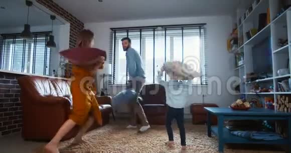 快乐的年轻白种人父亲和母亲享受有趣的枕头战斗与可爱的小儿子在现代轻家庭慢动作视频的预览图
