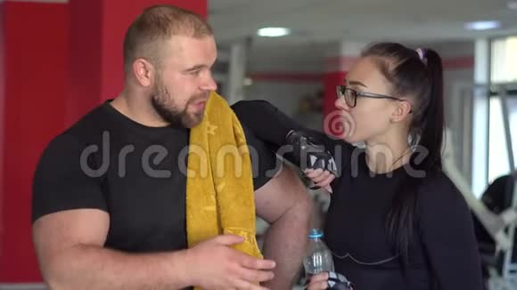 强壮的肌肉男和女朋友在健身房交谈视频的预览图