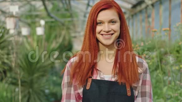 红发花匠女人在花棚里对着镜头看镜头笑容灿烂视频的预览图