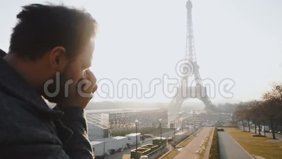 后景快乐的男性白人记者用老式电影摄影机慢镜头拍摄巴黎埃菲尔铁塔的照片视频的预览图