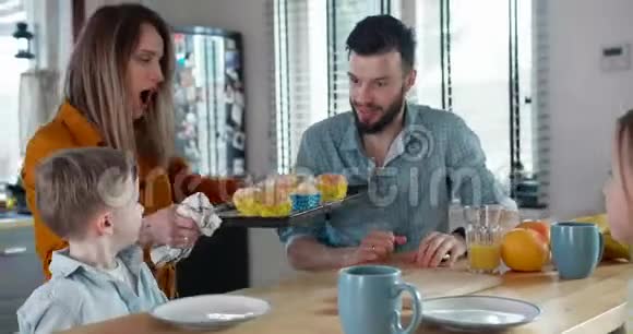 幸福的家庭在一起的概念年轻的高加索人的母亲和父亲闻到了热的新鲜松饼与孩子在家里慢动作视频的预览图