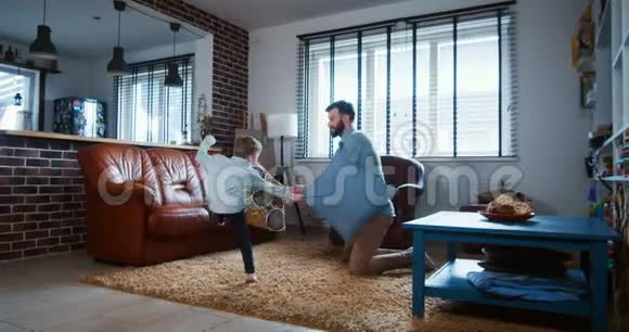 开朗年轻的欧洲爸爸和小可爱的儿子玩耍打架枕头在现代轻屋房间慢动作视频的预览图