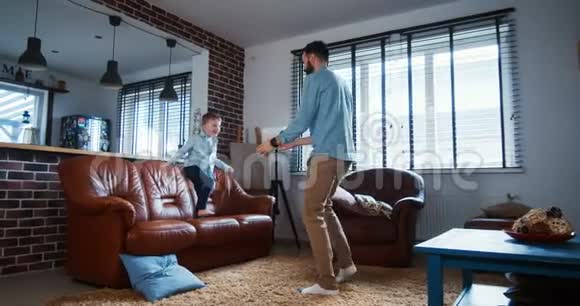 快乐的年轻白种人父亲把他的小儿子举得很高在现代轻客厅里玩得很开心慢动作视频的预览图