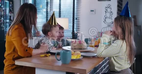 美丽快乐的白种人母亲帮助可爱的儿子在生日蛋糕上吹生日蛋糕与孩子和五彩纸屑慢动作视频的预览图