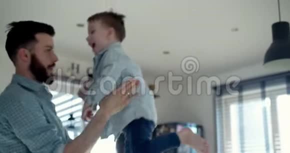 快乐的年轻白种人爸爸和可爱的小儿子在现代轻屋厨房玩耍家庭乐趣概念慢动作视频的预览图