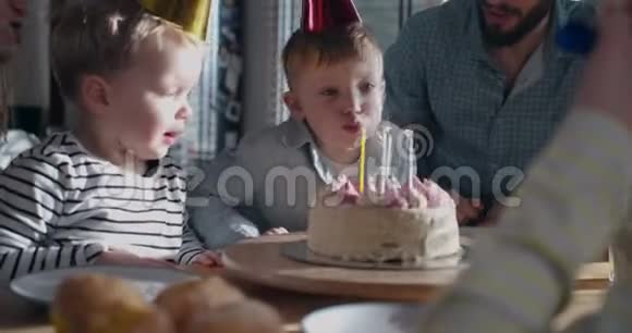 可爱快乐的小白种人男孩许愿吹生日蛋糕在有趣的庆祝与家庭慢动作视频的预览图