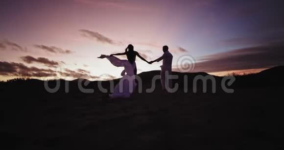 日落时分的浪漫时光对于一对年轻夫妇来说他们享受着一起走过布满沙石的田野的时光视频的预览图