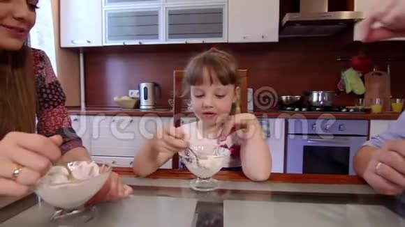 父母和女儿在家厨房吃冰淇淋可爱的小女孩在厨房吃冰淇淋爸爸视频的预览图