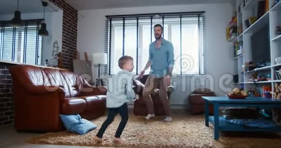 家庭乐趣在家的概念快乐的年轻白种人父亲和小儿子一起跳舞在客厅慢动作视频的预览图