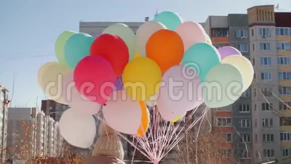 带着五颜六色气球束的女人走在城市街道的后景色手拿彩球的年轻女子视频的预览图