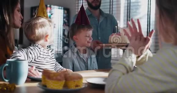 年轻的父亲为小白种人的儿子带来了生日蛋糕在家里有趣的聚会和家庭慢动作视频的预览图