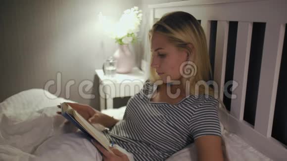 穿着睡衣的女人读完一本书就要睡觉了视频的预览图