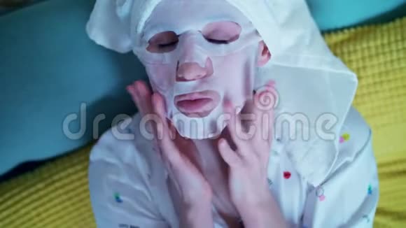 肖像可爱的年轻女士戴着化妆面料面具的女人头上戴着白色毛巾躺在沙发上视频的预览图