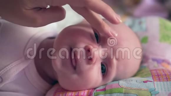 皮肤护理年轻的母亲抚摸婴儿的脸视频的预览图