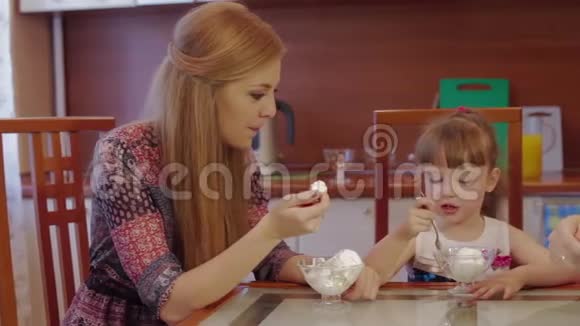 父母和女儿在厨房在家聊天吃冰淇淋可爱的小女孩在碗里吃冰淇淋视频的预览图