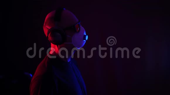 戴防护面罩的人在霓虹灯背景下听音乐耳机听耳机音乐的人视频的预览图