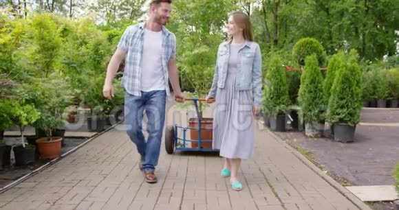 一对幸福的年轻夫妇在植物店刚买了一棵漂亮的盆栽树视频的预览图