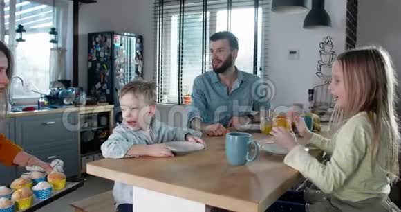 幸福的家庭观念年轻的高加索母亲带着松饼与父亲和两个可爱的孩子慢动作庆祝视频的预览图