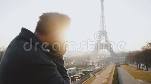 快乐职业摄影师男子拍摄巴黎埃菲尔铁塔背光照片与老式相机慢动作视频的预览图
