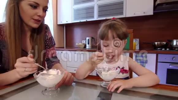 父母和女儿在家厨房吃冰淇淋可爱的小女孩在厨房的碗里吃冰淇淋视频的预览图