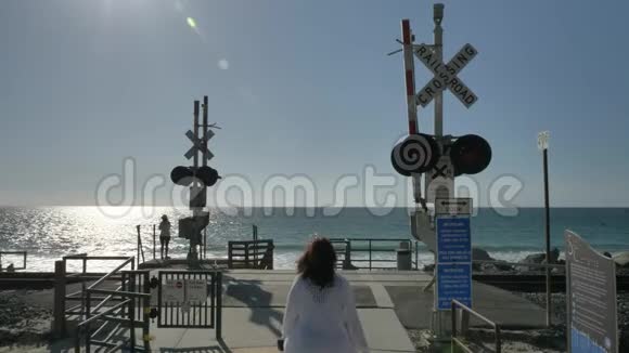 积极的老年妇女在加州的夏日步行穿过靠近海洋的铁路拥有美丽的风景视频的预览图