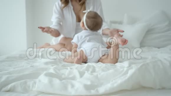 可爱的婴儿女孩爬在床上爬向妈妈视频的预览图