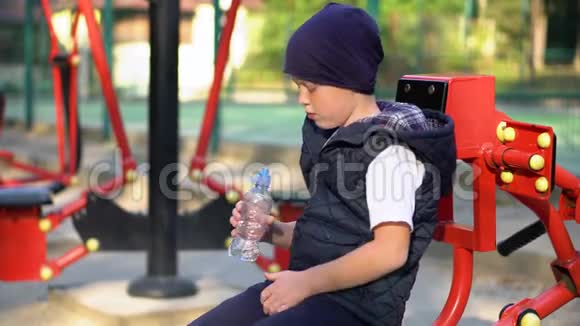 小男孩在室外公共健身器材附近饮水儿童运动视频的预览图