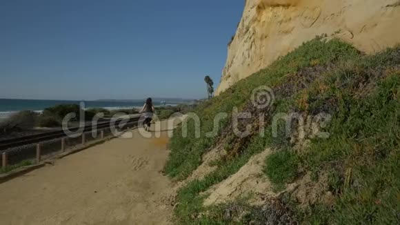 在加州圣克莱门特的夏日在靠近海洋的行人小径上散步的妇女拥有美丽的风景视频的预览图