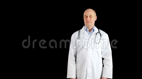 身穿医用长袍的秃头医生在黑色背景下向某处展示白人医生视频的预览图