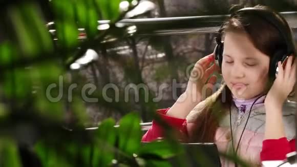 十几岁的女孩戴着耳机在笔记本电脑上工作在网上聊天在开放的阳台上春天阳光明媚的一天远程学习视频的预览图