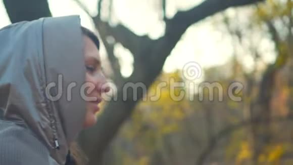孤独的概念秋天或春天公园里穿浅色夹克的女孩的肖像头罩里的女孩视频的预览图