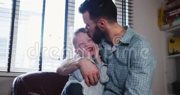 快乐的年轻白种人父亲接吻的肖像在现代轻屋慢动作中与可爱的微笑的小儿子玩耍视频的预览图