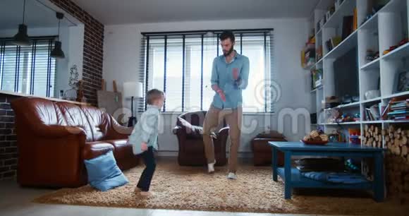 快乐年轻开朗的白种人父亲和小儿子在现代家庭客厅慢动作一起跳舞视频的预览图