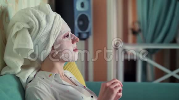 肖像画一位戴着化妆面料面具头上戴着一条白毛巾的妇女用指甲锉视频的预览图