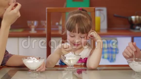 父母和女儿在厨房在家聊天吃冰淇淋可爱的小女孩笑着吃冰视频的预览图
