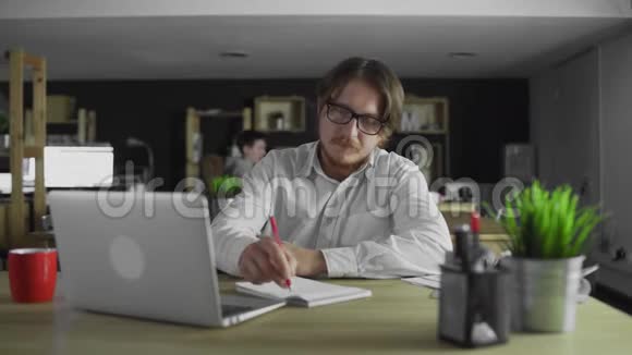 年轻的经理一个人坐在办公桌前写字视频的预览图