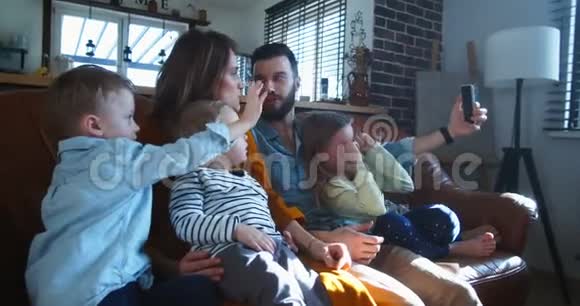 快乐年轻的欧洲家庭与孩子聊天与朋友在智能手机在线视频通话在家里慢动作视频的预览图