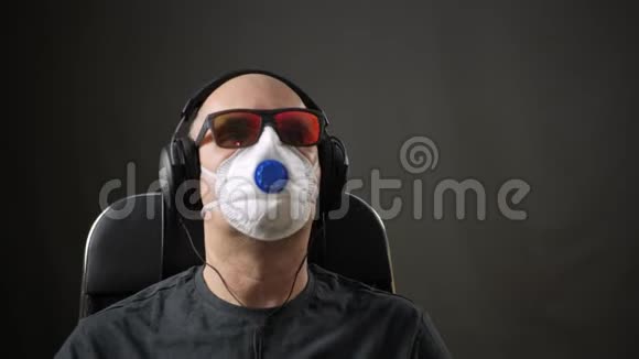 戴防护面罩的人坐在椅子上听音乐耳机戴防护面罩的人听音乐视频的预览图